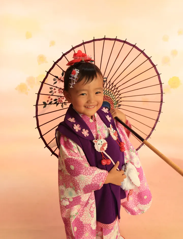 七五三の記念撮影 ピンクの被布で赤い和傘を持つ女の子